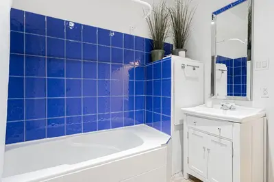 a blue tiled bathroom with a tub and a sink at Suite La Madame - Designer Downtown Nest in Montréal