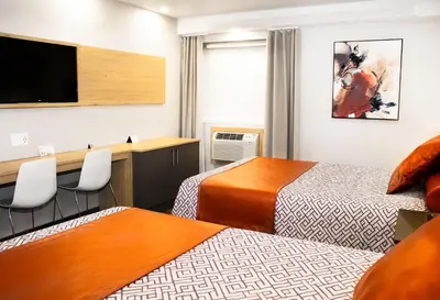a hotel room with two beds and a flat screen tv at Hôtel-Motel & Suites Idéal Montréal in Montréal