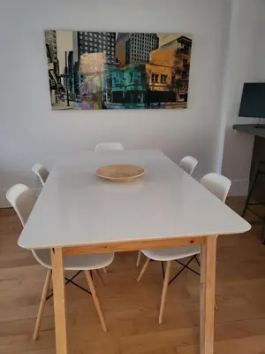 a white table with chairs and a painting on the wall at Super appartement proche metro in Montréal