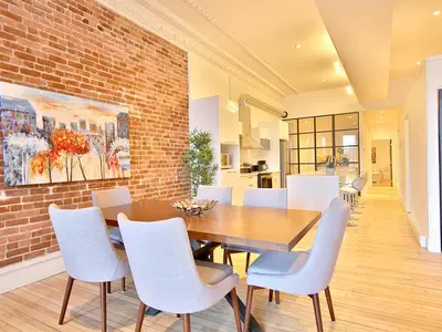 a dining room with a wooden table and white chairs at Yulux Old Montreal luxurious apartments in Montréal