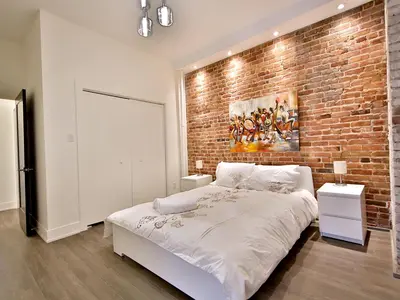 a bedroom with a brick wall and a bed at Yulux Old Montreal luxurious apartments in Montréal