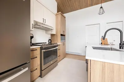 a kitchen with wooden cabinets and a sink at Ski Condo & Spa - L'Elegance Des Sommets in Adstock