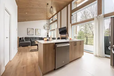 a kitchen and living room with a large window at Ski Condo & Spa - L'Elegance Des Sommets in Adstock
