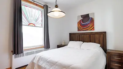 a bedroom with a white bed and a window at Downtown Heritage House and Free Parking in Joliette
