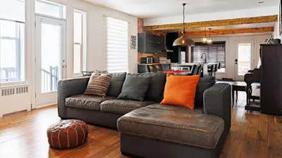 a living room with a couch and a kitchen at Downtown Heritage House and Free Parking in Joliette