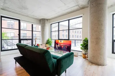 a living room with a couch and a table and windows at Old Port Gem - Charming 2 bdr in Prime Location in Montréal