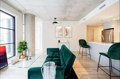 a living room with a green couch and a kitchen at Old Port Gem - Charming 2 bdr in Prime Location in Montréal