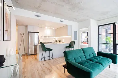 a living room with a green couch and a kitchen at Old Port Gem - Charming 2 bdr in Prime Location in Montréal