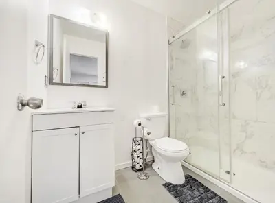 a white bathroom with a toilet and a shower at Superbe 2 chambres à Griffintown in Montréal