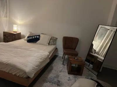 a bedroom with a bed and a chair and a mirror at Cosy Cabin apt in Montreal in Montréal
