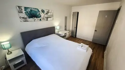 a small bedroom with a white bed and two tables at Private rooms in a shared three bedroom apartment in Montréal