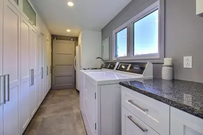 a kitchen with white cabinets and a sink and a window at La Brise O-Lac in Sherbrooke