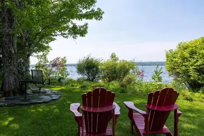 two chairs sitting in the grass by the water at La Brise O-Lac in Sherbrooke
