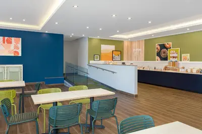 a waiting room with tables and chairs and a counter at Spark By Hilton Montreal Midtown in Montréal