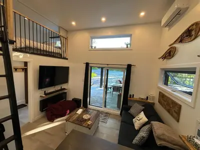a living room with a couch and a tv at Spa - Chalet Sur Les Sentiers du Pic-Bois in Adstock