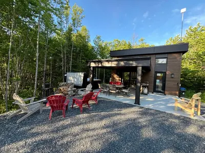 a small cabin with red chairs and a table at Spa - Chalet Sur Les Sentiers du Pic-Bois in Adstock