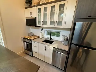 a kitchen with white cabinets and stainless steel appliances at Spa - Chalet Sur Les Sentiers du Pic-Bois in Adstock