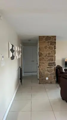 a living room with a stone wall and a couch at Cozy Riverside Home Retreat in Laval