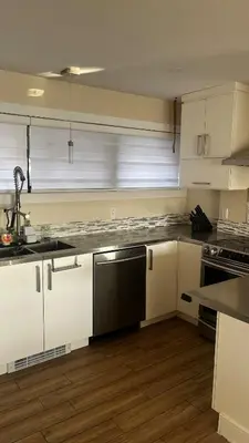 a kitchen with white cabinets and a black dishwasher at Cozy Riverside Home Retreat in Laval