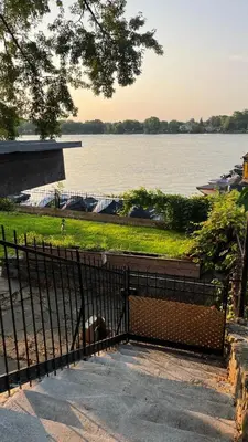 a dog laying behind a fence next to a body of water at Cozy Riverside Home Retreat in Laval
