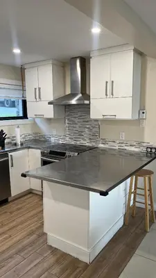a kitchen with white cabinets and a counter top at Cozy Riverside Home Retreat in Laval