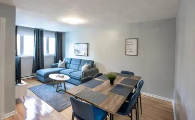 a living room with a table and a blue couch at 3BR 6Beds 5min Walk Metro Free Parking Place Bell in Laval