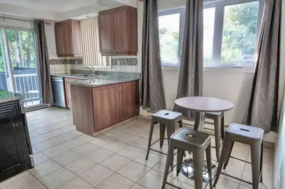 a kitchen with a table and some stools in it at 3BR 6Beds 5min Walk Metro Free Parking Place Bell in Laval