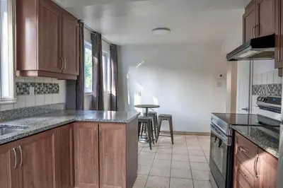 a kitchen with wooden cabinets and a table at 3BR 6Beds 5min Walk Metro Free Parking Place Bell in Laval