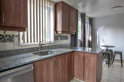 a kitchen with wooden cabinets and a sink and a window at 3BR 6Beds 5min Walk Metro Free Parking Place Bell in Laval