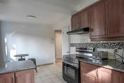 a kitchen with wooden cabinets and a stove top oven at 3BR 6Beds 5min Walk Metro Free Parking Place Bell in Laval