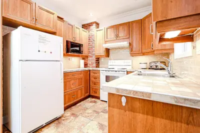 a kitchen with wooden cabinets and a white refrigerator at Royal Level-5 bedrooms avec 2 places de parking in Montréal