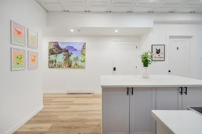 a white kitchen with a counter and paintings on the wall at Chambre 2 - appartement 2 dans un appartement PARTAGÉ in Montréal