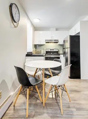 a kitchen with a table and chairs and a clock on the wall at Séjour agréable à Griffintown 2 chambres in Montréal