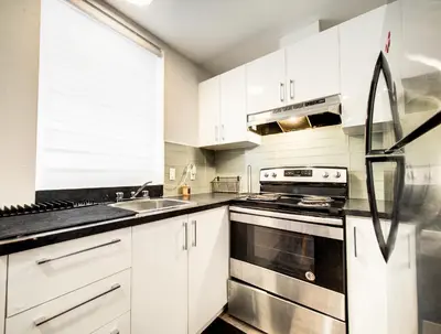 a kitchen with white cabinets and stainless steel appliances at Séjour agréable à Griffintown 2 chambres in Montréal