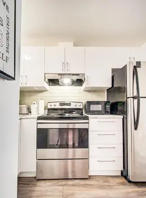 a kitchen with white cabinets and a stainless steel oven at Chic & spacieux 2 chambres à Griffintown in Montréal