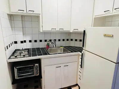 a white kitchen with a sink and a refrigerator at Modern City Living in the Golden Square Mile in Montréal