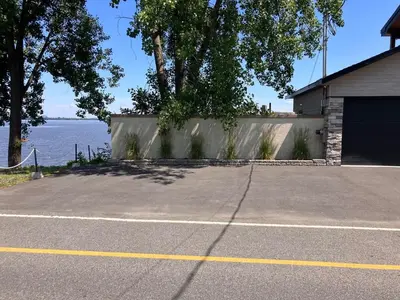 a parking lot in front of a house with the water at Modern apartment with magnificent views in Vaudreuil-Dorion