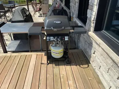 a grill sitting on a deck next to a building at Modern apartment with magnificent views in Vaudreuil-Dorion