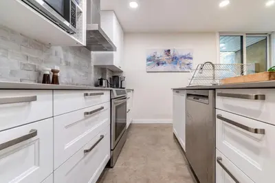 a kitchen with white cabinets and stainless steel appliances at une retraite de qualité au niveau du jardin en centre-ville in Montréal