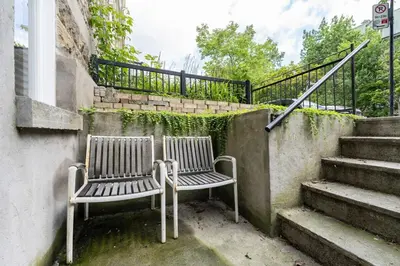two chairs sitting on the side of a building with stairs at une retraite de qualité au niveau du jardin en centre-ville in Montréal