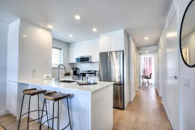 a white kitchen with a sink and a refrigerator at Tiny Penthouse Big Balcony Central & Cozy in Montréal