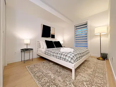 a white bedroom with a bed and a window at Tiny Penthouse Big Balcony Central & Cozy in Montréal
