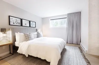 a white bedroom with a large bed and a window at Chalet Mid-Century - Lakeside Joseph - Le Charlo in Saint-Pierre-Baptiste