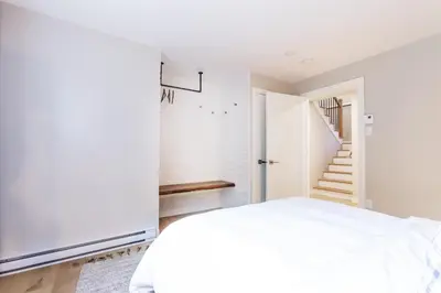 a bedroom with a white bed and a staircase at Chalet Mid-Century - Lakeside Joseph - Le Charlo in Saint-Pierre-Baptiste
