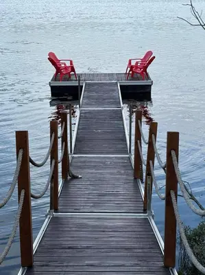 two red chairs sitting on a dock in the water at Chalet Mid-Century - Lakeside Joseph - Le Charlo in Saint-Pierre-Baptiste