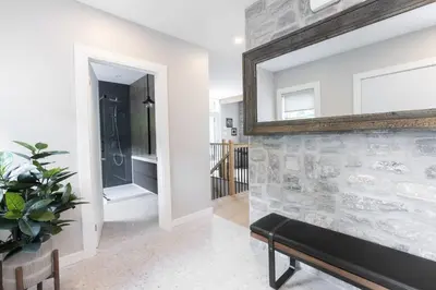 a living room with a stone wall and a mirror at Chalet Mid-Century - Lakeside Joseph - Le Charlo in Saint-Pierre-Baptiste