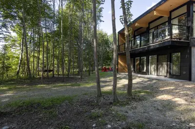 a house in the woods with a lot of windows at Chalet Mid-Century - Lakeside Joseph - Le Charlo in Saint-Pierre-Baptiste
