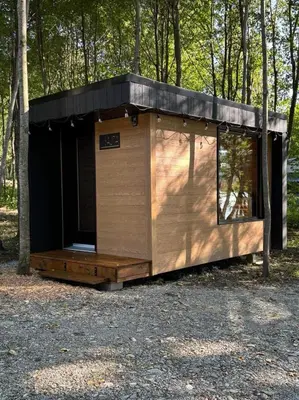 a cabin in the woods with a black roof at Chalet Mid-Century - Lakeside Joseph - Le Charlo in Saint-Pierre-Baptiste