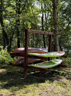 a wooden bench with surfboards sitting in the grass at Chalet Mid-Century - Lakeside Joseph - Le Charlo in Saint-Pierre-Baptiste