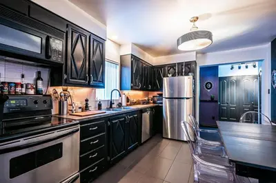 a kitchen with black cabinets and stainless steel appliances at Cohabs Montréal in Montréal